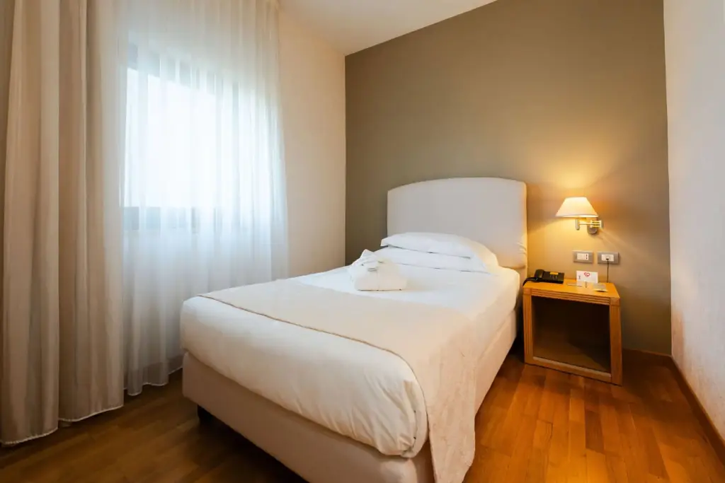Camera accogliente con letto singolo e luce calda.